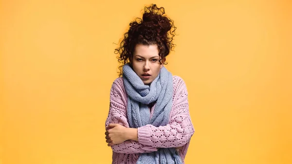 Mujer insatisfecha congelándose en suéter de punto y bufanda aislada en naranja - foto de stock