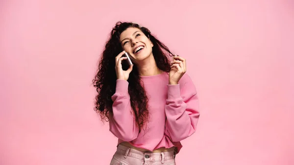 Mujer feliz hablando en el teléfono inteligente y riendo aislado en rosa - foto de stock