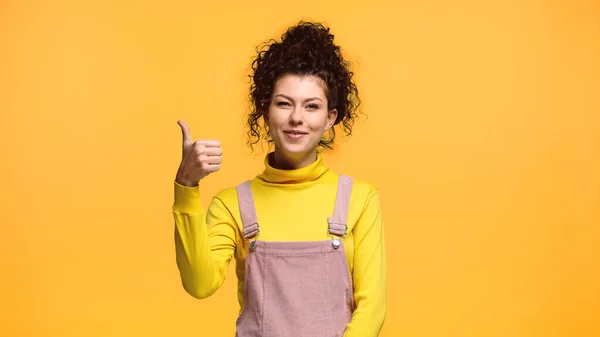 Femme joyeuse regardant la caméra et montrant pouce vers le haut isolé sur orange — Photo de stock