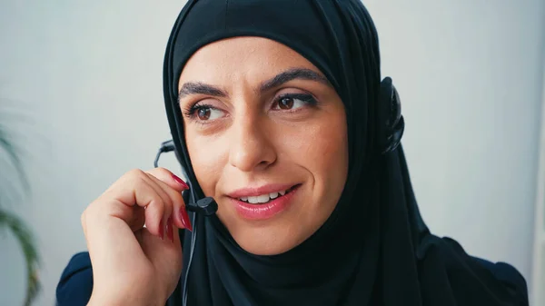 Muslim operator of call center using headset and smiling in office — Stock Photo