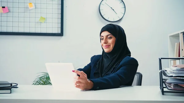 Sorridente donna d'affari musulmana che utilizza tablet digitale in ufficio — Foto stock