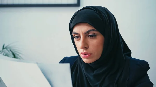 Empresária muçulmana no hijab trabalhando com documentos desfocados no cargo — Fotografia de Stock