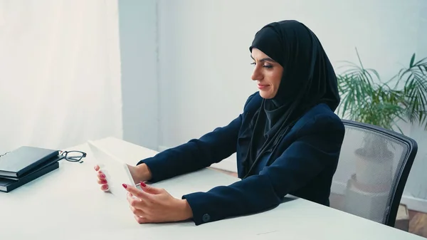 Pleased muslim businesswoman using digital tablet in office — Stock Photo