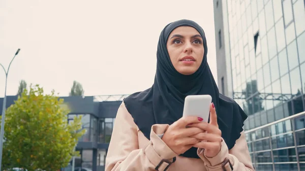 Young muslim woman in hijab chatting on smartphone outside — Stock Photo