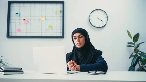 Selbstbewusste muslimische Geschäftsfrau mit Videoanruf auf Laptop im Büro — Stockfoto