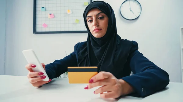 Empresaria musulmana usando smartphone y tarjeta de crédito - foto de stock