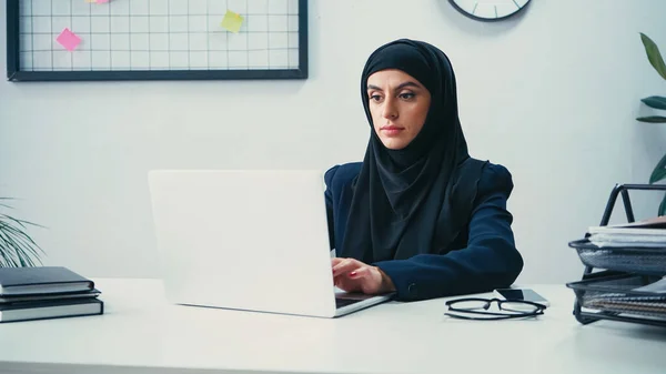 Молода мусульманка в хіджабі використовує ноутбук в офісі — стокове фото