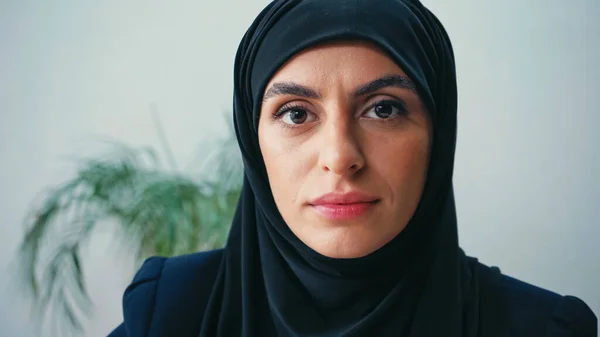 Primer plano de la joven mujer de negocios musulmana en hijab mirando a la cámara en la oficina - foto de stock