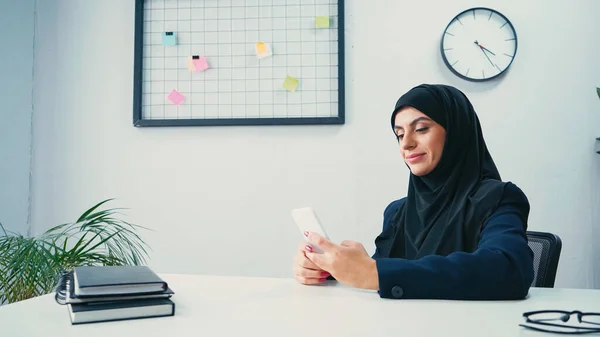 Donna d'affari musulmana che utilizza smartphone in ufficio — Foto stock