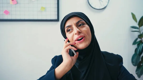 Mulher de negócios muçulmana alegre no hijab falando no smartphone — Fotografia de Stock