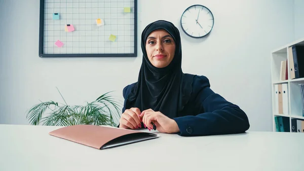 Mulher de negócios muçulmana no hijab sentado na mesa com pasta — Fotografia de Stock