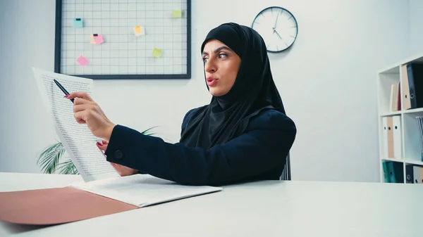 Donna d'affari musulmana in hijab che punta con penna al documento in ufficio moderno — Foto stock