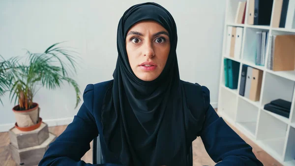 Femme d'affaires arabe choquée dans le hijab regardant la caméra dans le bureau — Photo de stock