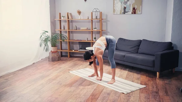 Fitte Sportlerin streckt sich zu Hause auf Fitnessmatte zurück — Stockfoto