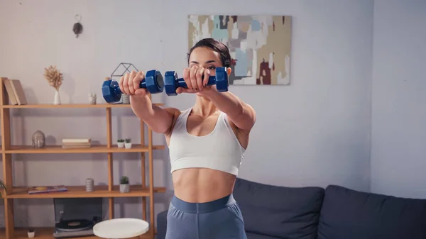 Ajuste deportista haciendo ejercicio con mancuernas en casa - foto de stock