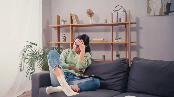 Upset student sitting near paper folder on couch — Stock Photo
