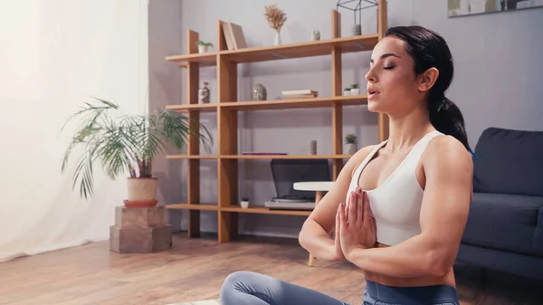 Sportswoman meditating with closed eye at home — Stock Photo