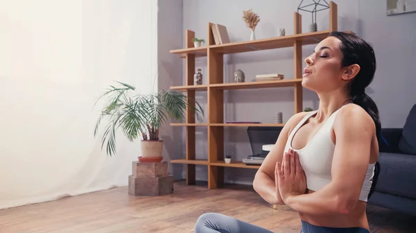 Side view of sportswoman meditating in living room — Stock Photo