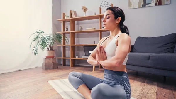 Mujer morena bonita meditando en esterilla de yoga - foto de stock