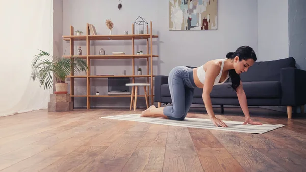 Junge Frau steht auf Fitnessmatte im Wohnzimmer — Stockfoto