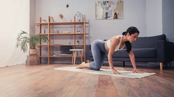 Giovane donna che esercita sul tappeto fitness a casa — Foto stock