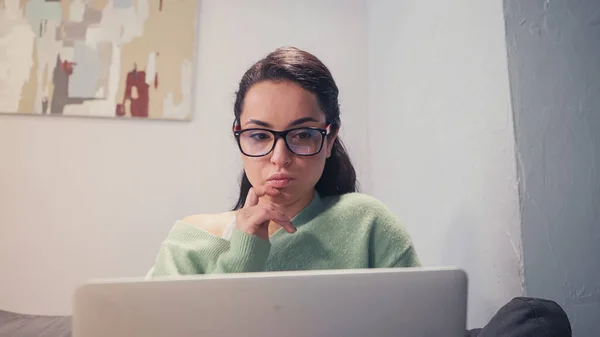 Libero professionista pensieroso che guarda il computer portatile sfocato a casa — Foto stock