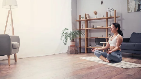 Vista lateral de la joven mujer meditando en la sala de estar - foto de stock