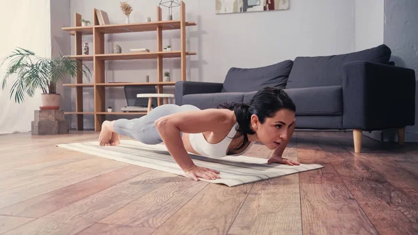 Женщина делает отжимания на фитнес-коврик дома — стоковое фото
