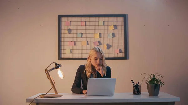 Jeune femme d'affaires travaillant sur ordinateur portable près de la lampe dans le bureau — Photo de stock