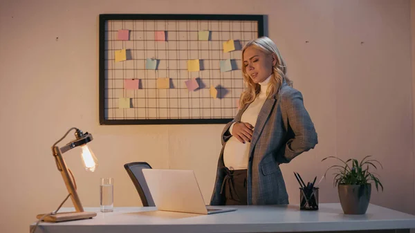 Втомилася вагітна бізнес-леді, дивлячись на ноутбук в офісі — стокове фото