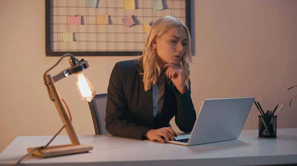 Femme d'affaires utilisant un ordinateur portable près de la lampe sur la table dans le bureau — Photo de stock
