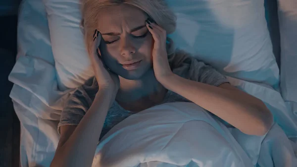 Top view of young woman suffering from headache in bedroom — Stock Photo