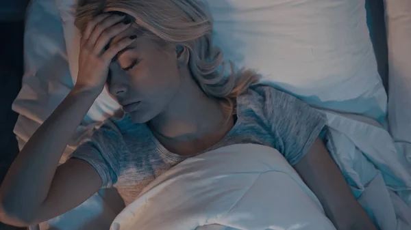 Vista dall'alto della donna malata che tiene la mano sulla fronte in camera da letto — Foto stock