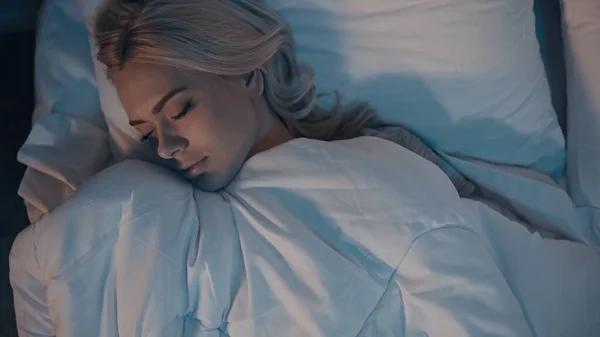Vista superior de la mujer durmiendo en ropa de cama blanca - foto de stock