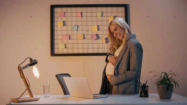 Femme d'affaires enceinte ayant un appel vidéo sur un ordinateur portable au bureau — Photo de stock