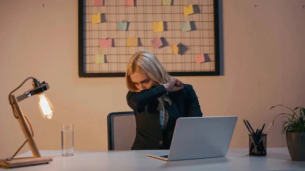 Mujer de negocios enferma tosiendo cerca de la mesa de trabajo en la oficina - foto de stock