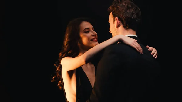 Happy young couple looking at each other while dancing slow isolated on black — Stock Photo