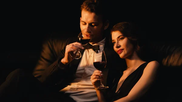Задоволена пара тримає окуляри червоного вина ізольовані на чорному — стокове фото