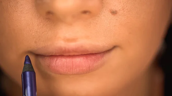 Vista parcial de la mujer aplicando delineador de labios púrpura en los labios - foto de stock