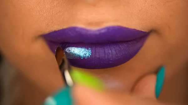 Abgeschnittene Ansicht einer Frau, die Lipgloss mit Schimmer auf lila Lippen aufträgt — Stockfoto