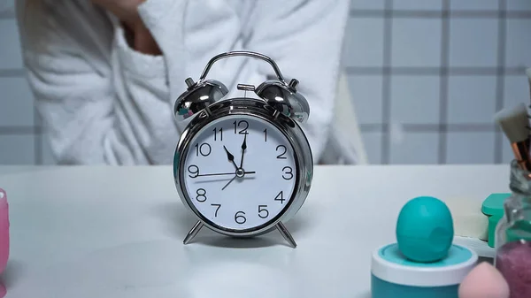 Cropped view of woman in bathrobe near alarm clock — Stock Photo