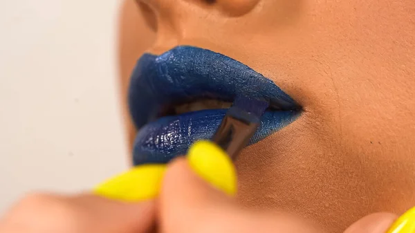 Vista recortada de la mujer aplicando lápiz labial azul con cepillo cosmético aislado en blanco - foto de stock