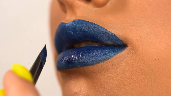 Vue partielle de la femme appliquant rouge à lèvres bleu avec pinceau cosmétique isolé sur blanc — Photo de stock