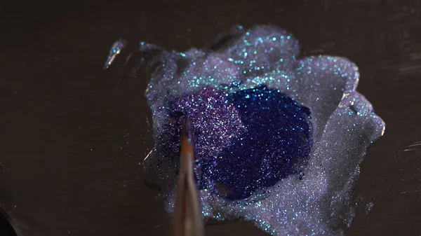 Верхний вид кисти возле сверкающей фиолетовой жидкости с мерцанием — стоковое фото
