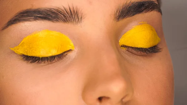 Visão parcial da mulher aplicando sombra olho cremoso amarelo com escova cosmética — Fotografia de Stock