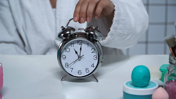 Cropped view of woman in bathrobe taking alarm clock — Stock Photo