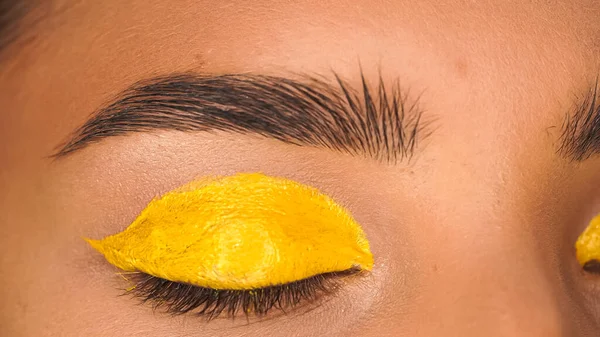 Частичный взгляд женщины с закрытым глазом и желтой сливочной тенью для глаз — Stock Photo