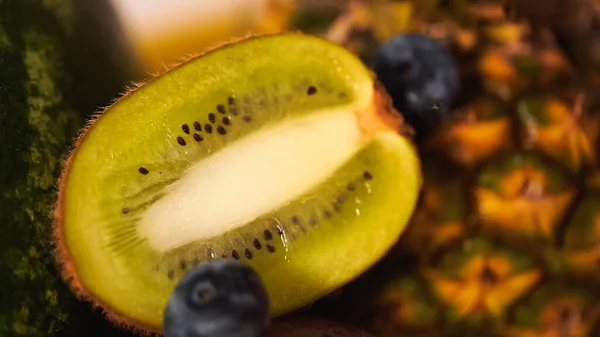 Close up of kiwi fruit near berries and blurred pineapple — Stock Photo