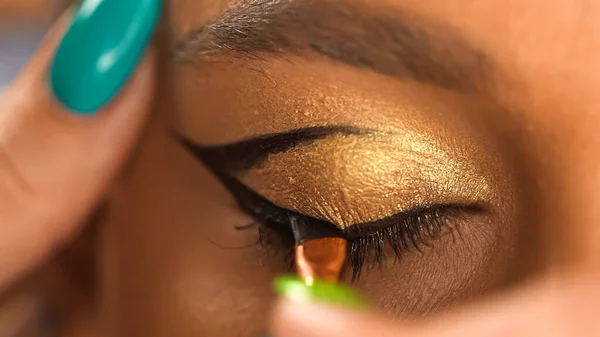 Vue partielle du modèle afro-américain avec oeil fermé application eye liner avec pinceau cosmétique — Photo de stock
