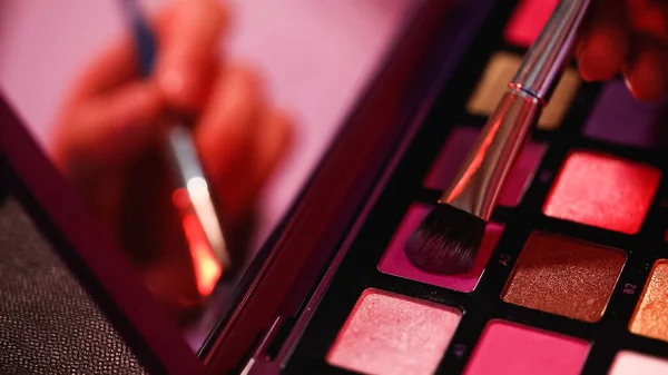 Vista ritagliata della donna che applica ombretto viola sulla spazzola cosmetica — Foto stock